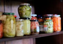Słoiki z kolorowymi domowymi przetworami ustawione na drewnianej półce