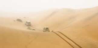 Dwa auta terenowe jadą przez rozległe wydmy w Namibii, region Hardap