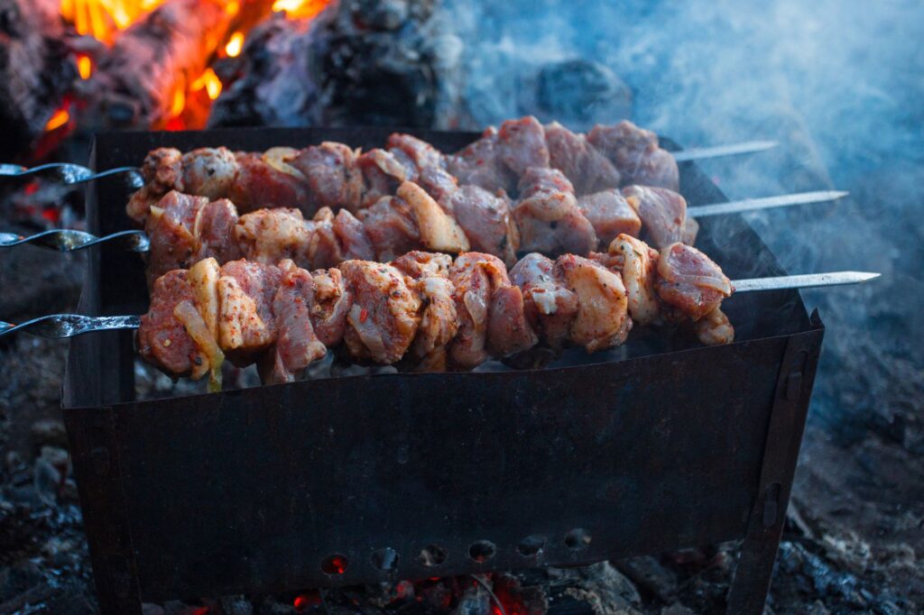 Szaszłyki wieprzowe skwierczące na grillu nad otwartym ogniem